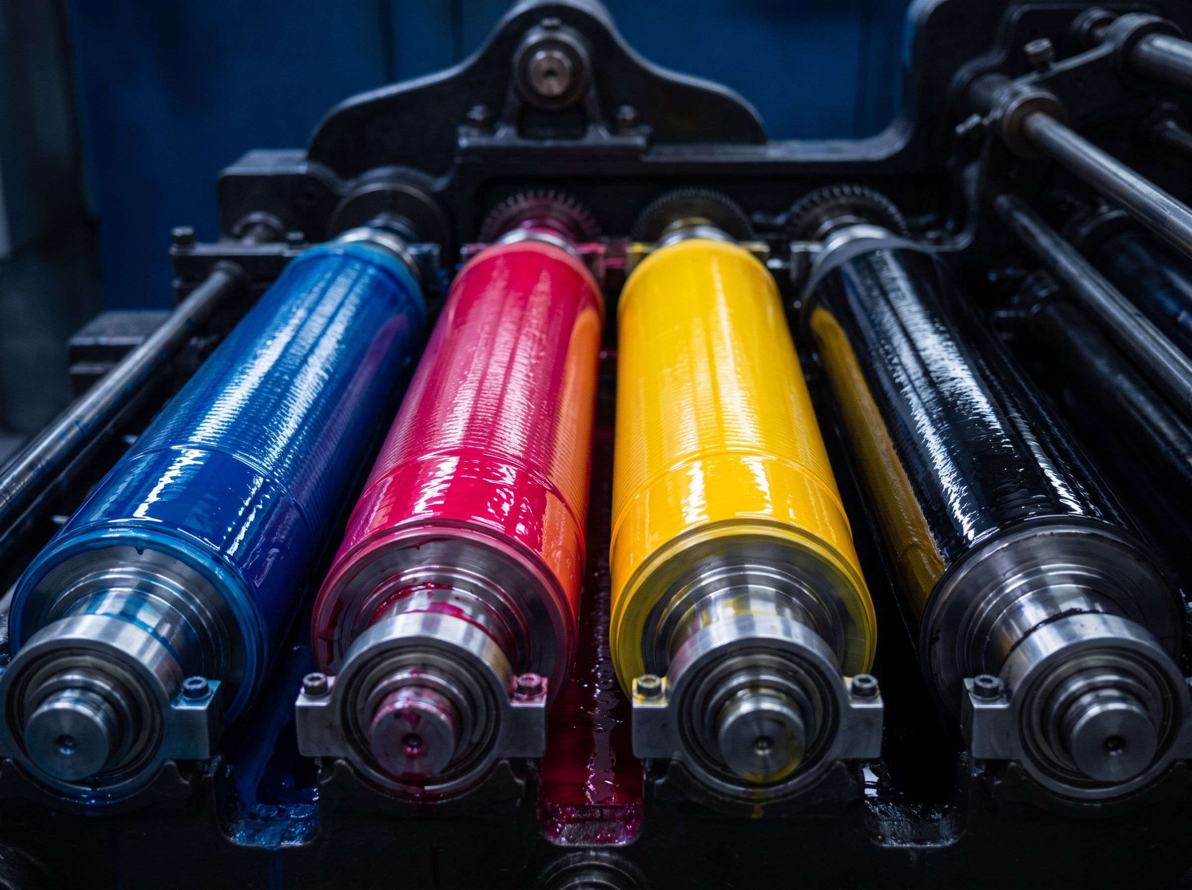 Printing press ink rollers coated in cyan, magenta, yellow and black ink